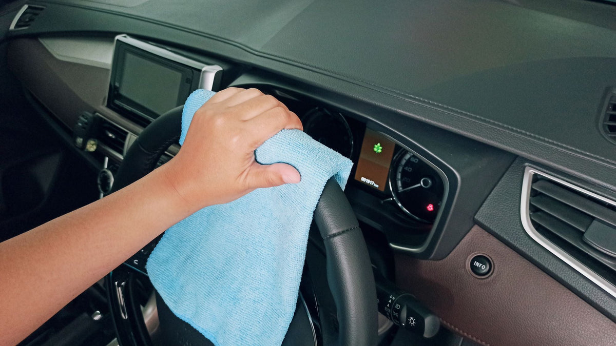 Hand wiping a leather steering wheel with a microfibre cloth