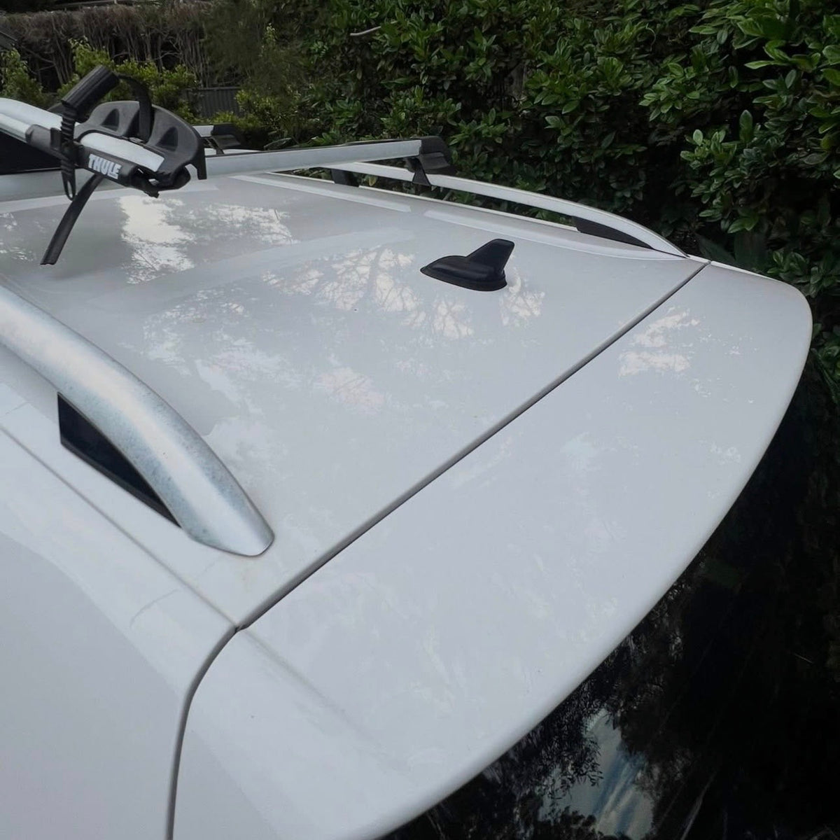 After: white car roof clean and glossy beneath the roof racks