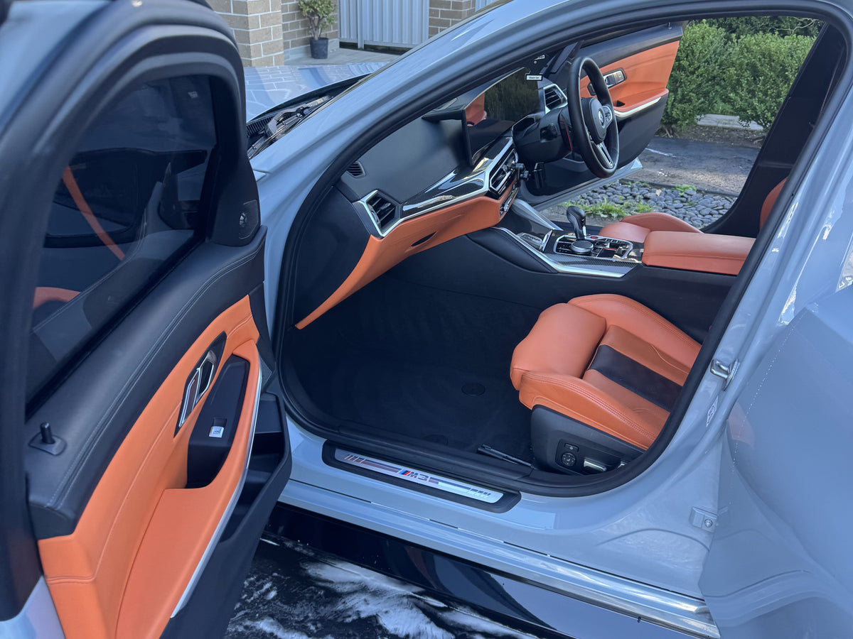 BMW interior with orange leather seats and door trim after an interior detail