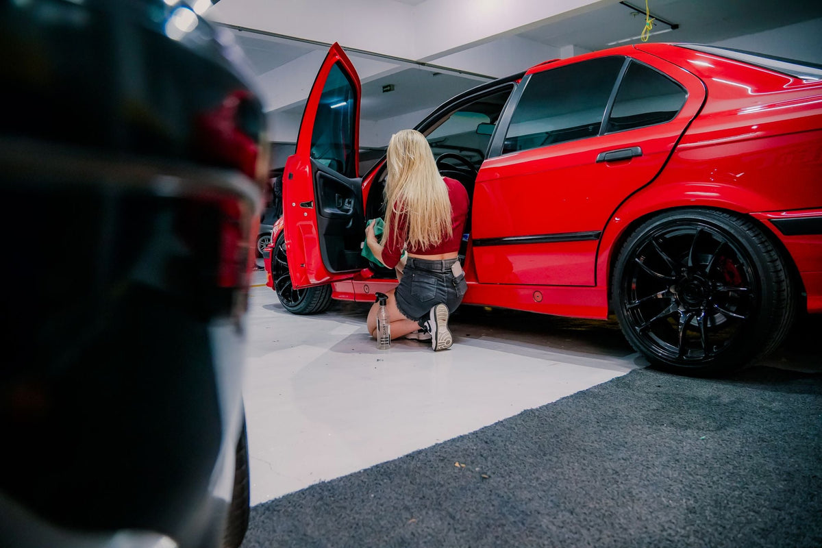 Detailer cleaning the interior of a red BMW before sale