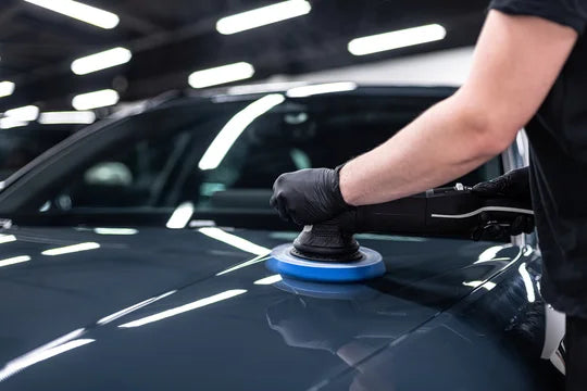 Detailer machine polishing dark paint during paint correction