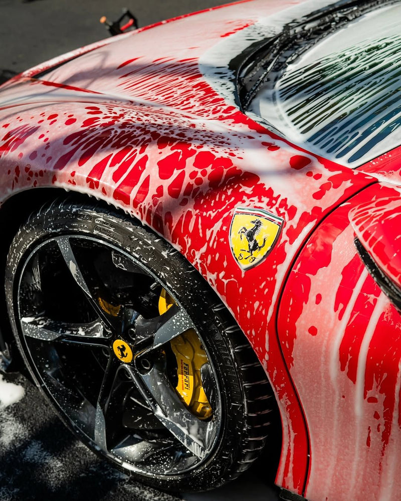 Red Ferrari covered in snow foam during a hand wash
